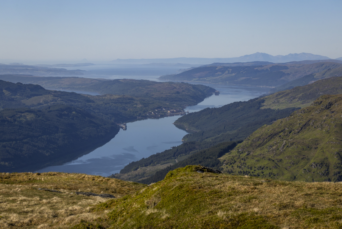 View down Loch Long flanked by wooded hillsides with the hills of Arran in the distance, Arrochar, Scotland, UK, May